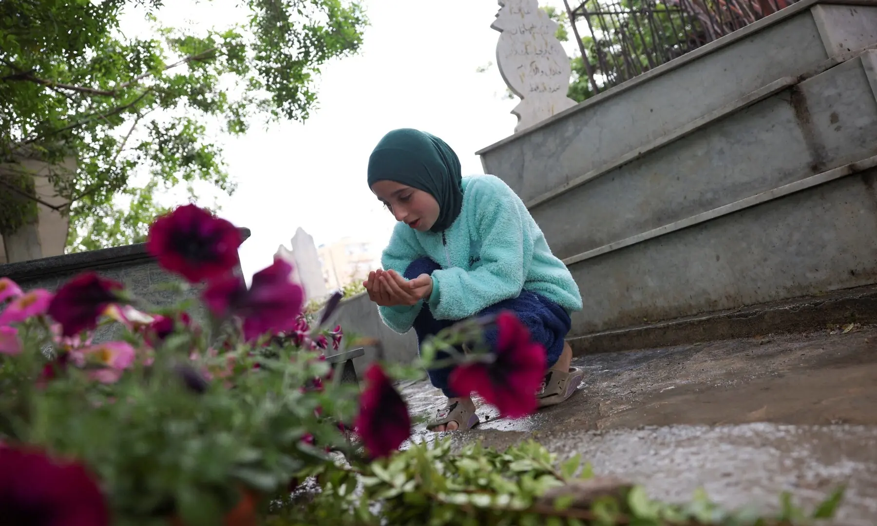 A displaced girl from Tyre prays in front of a grave at a Shi&rsquo;ite cemetery, on the day of Eid al-Fitr, marking the end of the Muslim holy fasting month of Ramadan, following an escalation between Hezbollah and Israel amid the U.S.-Israeli conflict with Iran, in Sidon, Lebanon, March 20, 2026. &mdash; Reuters
