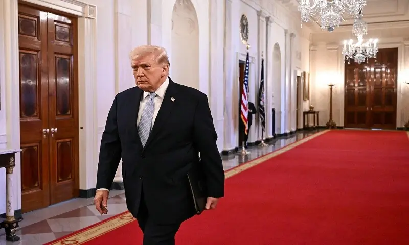 US President Donald Trump walks through the Cross Hall as he arrives for a ceremony to present the Commander-in-Chief Trophy to the Navy Midshipmen football team of the United States Naval Academy in the East Room of the White House in Washington, DC, on March 20, 2026. &mdash; AFP