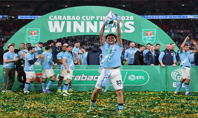MANCHESTER City&rsquo;s Nico O&rsquo;Reilly poses with the League Cup trophy as team-mates celebrate after defeating Arsenal in the final at the Wembley Stadium.&mdash;AFP