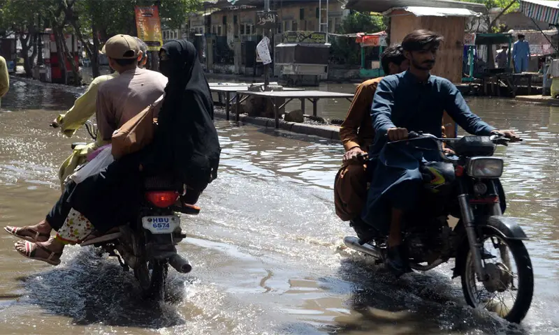 HYDERABAD: Motorcyclists ride down a waterlogged road after rain in parts of the city.&mdash;Umair Ali