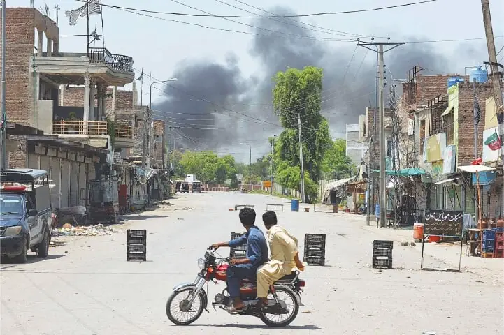 Men riding a bike turn back from a roadblock as they watch smoke rising, following an explosion after suspected militants attempted to storm the Bannu cantonment&mdash;AFP/File