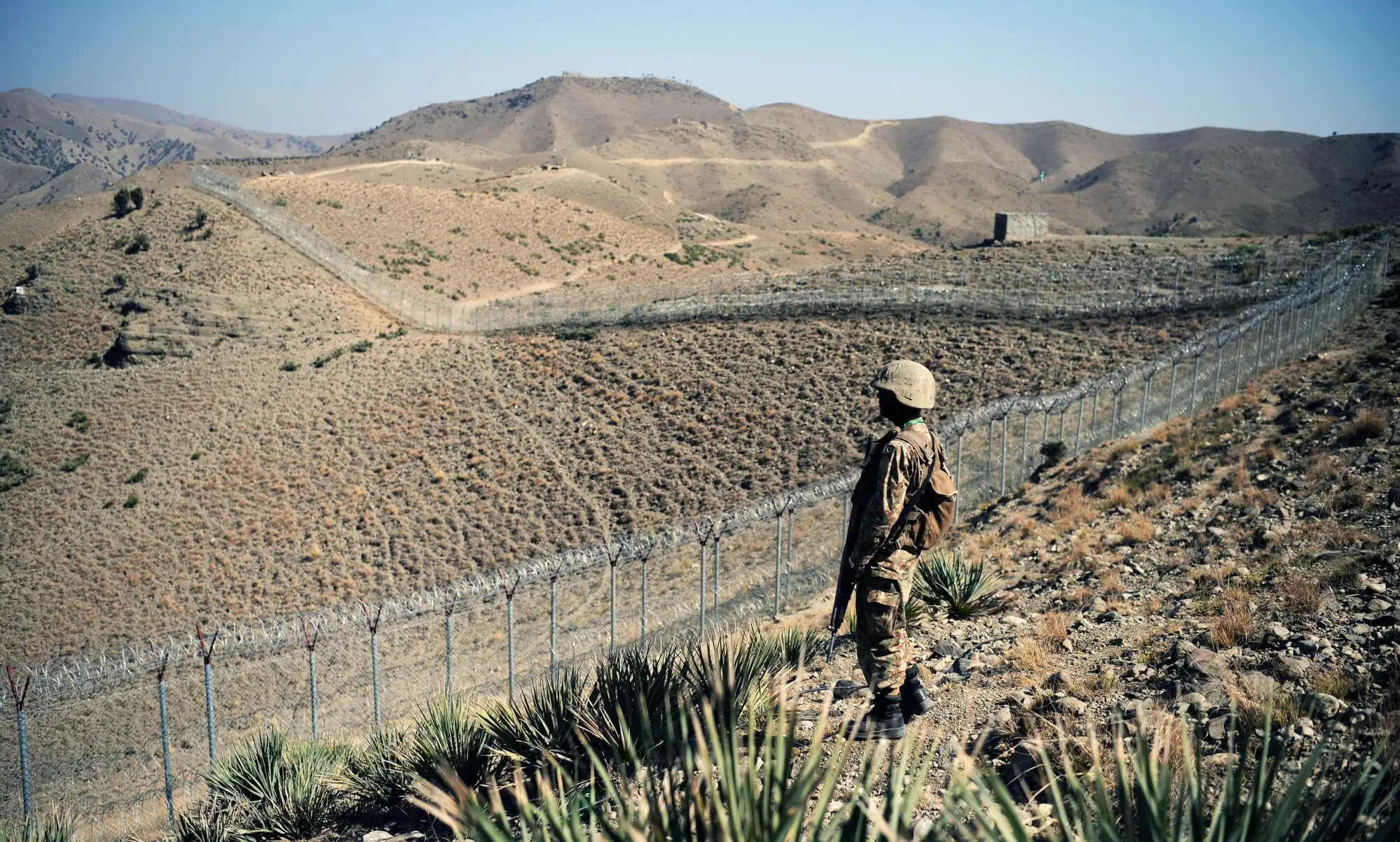 A Pakistani soldier keeps vigil next to a newly fenced border fencing along Afghan border at Kitton Orchard Post in Pakistan&rsquo;s North Waziristan tribal agency on October 18, 2017.
The Pakistan military vowed on October 18 a new border fence and hundreds of forts would help curb militancy, as it showcased efforts aimed at sealing the rugged border with Afghanistan long crossed at will by insurgents.   / AFP PHOTO / AAMIR QURESHI &mdash; AFP or licensors