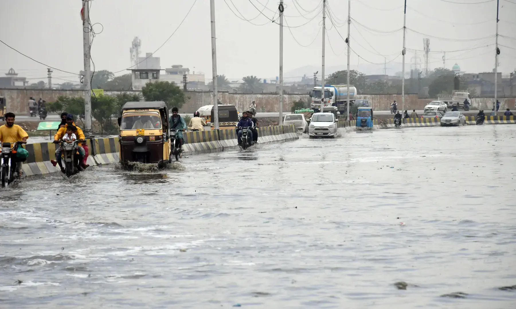 People struggle to move forward in a street with stangnant  rainwater after heavy rains and strong winds in Karachi on March 20. &mdash;  Online photo by Sabir Mazhar