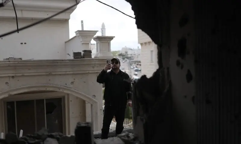A man takes a photograph as he surveys the damage to a house following a projectile strike in the Arab-Israeli city of Kfar Qassem on March 26, 2026. &mdash;AFP