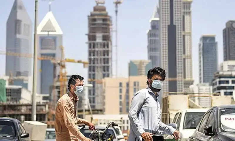 Migrant workers walk pushing bicycles along a street in Dubai&rsquo;s Satwa district in this file photo. &mdash; AFP/File