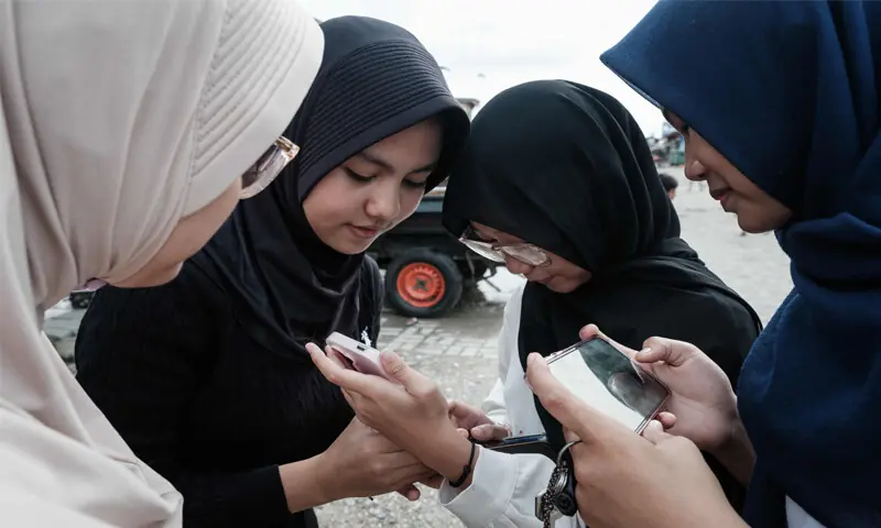 SCHOOLGIRLS use their smartphones on a street in Jakarta.&mdash;AFP