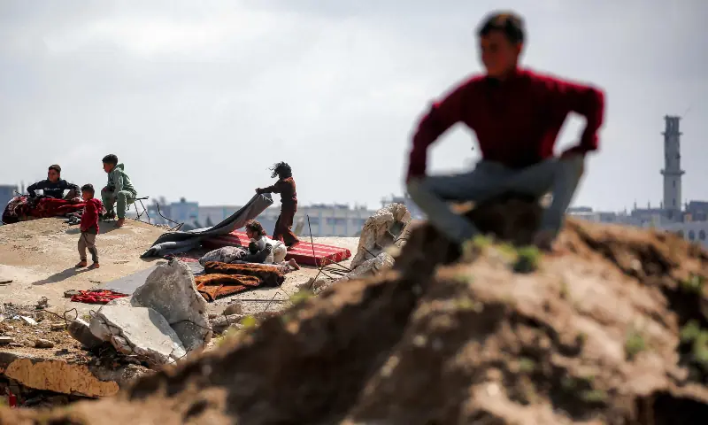 Children sit on the rubble of destroyed buildings at the Bureij camp for Palestinian refugees in the central Gaza Strip on March 27, 2026. &mdash; AFP