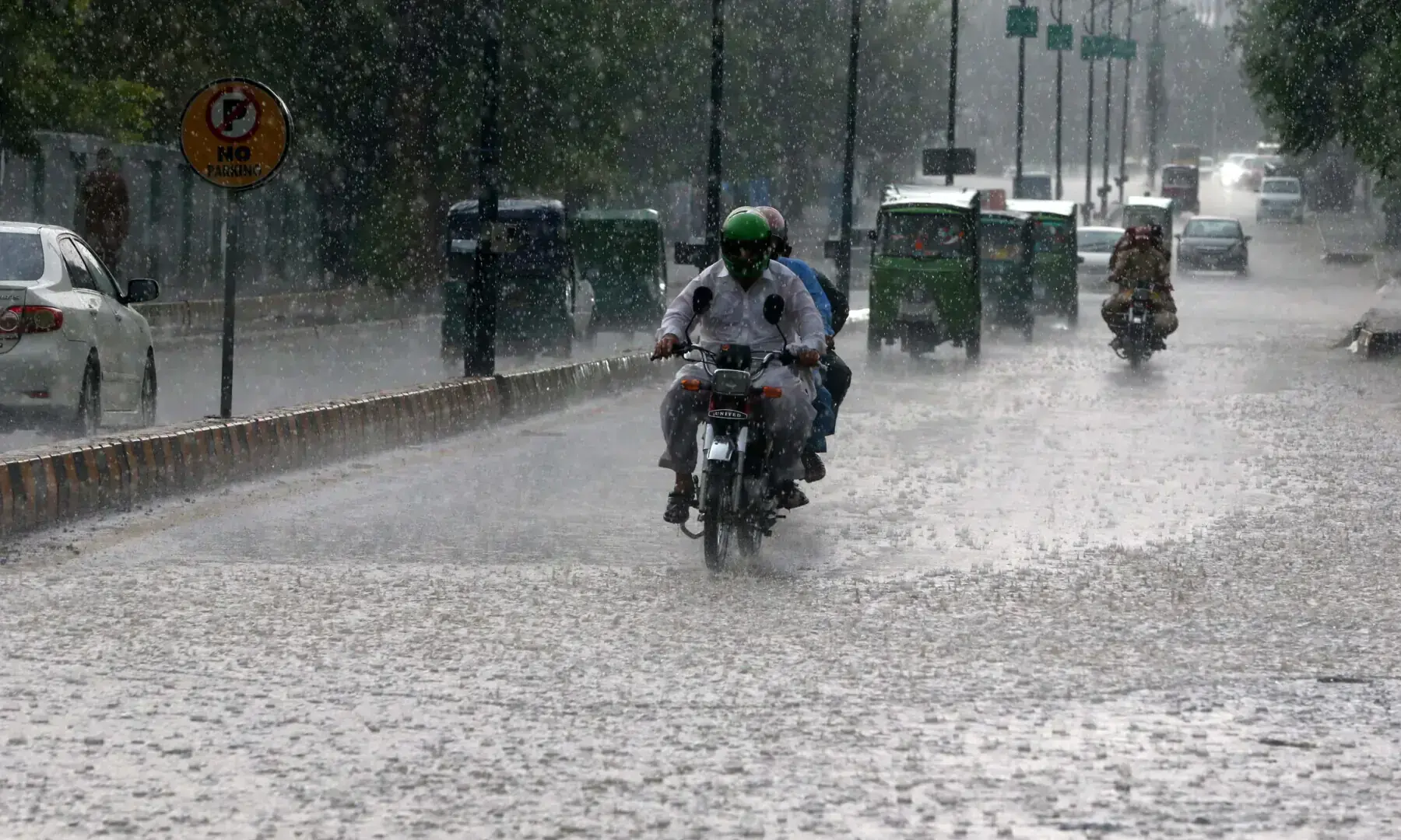 Bike riders and motorists pass through rain water accumulated on road at Sher Shah Suri Road, Peshawar on Aug 24, 2025. &mdash; Photo by Shahbaz Butt/White Star/File