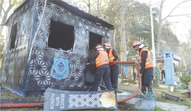  Firefighters douse a fire in a burnt security checkpost on a green belt along Red Zone on Constitution Avenue in Islamabad on Sunday. &mdash; White Star 