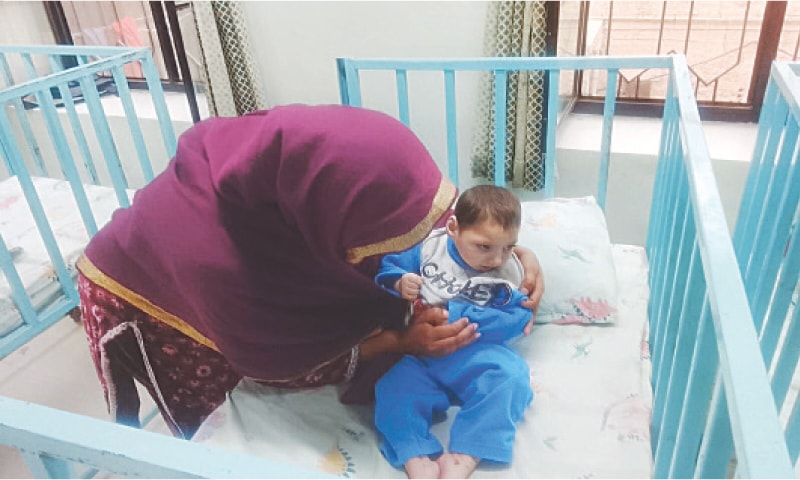 A caretaker comforts a special child at the centre. &mdash; Dawn