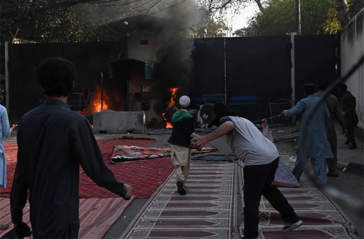 DEMONSTRATORS throw rocks after setting fire to the US consulate gate in Lahore.&mdash;M. Arif / White Star