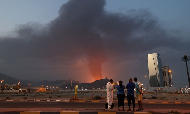 Workers look at a tall plume of black smoke following an explosion in the UAE&rsquo;s Fujairah industrial zone &mdash;AFP / Reuters