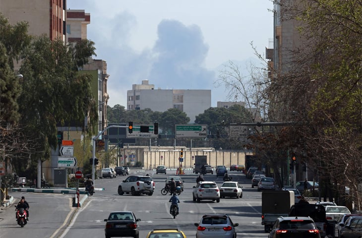 TRAFFIC is seen on a busy street in Tehran, even as a cloud of smoke rises following US-Israeli airstrikes in the Iranian capital.&mdash;AFP