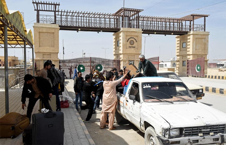 PAKISTANI nationals load their belongings onto a vehicle at the Pakistan-Iran border in Taftan, upon their arrival from Iran.&mdash;AFP