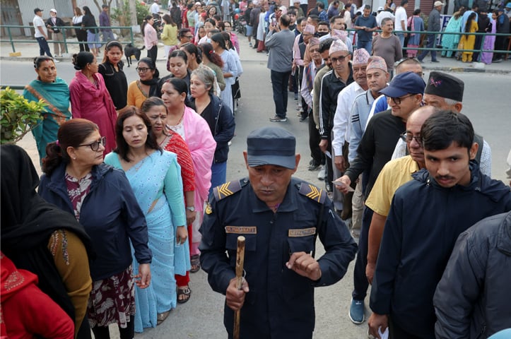 VOTERS stand in queues outside a polling station in Damak as a policeman walks by.&mdash;Reuters