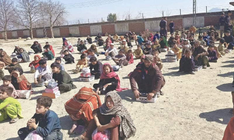Needy people gather at a school in Lowi Mamund tehsil of Bajaur district to receive goods under Ramazan Relief Package. &mdash; Dawn