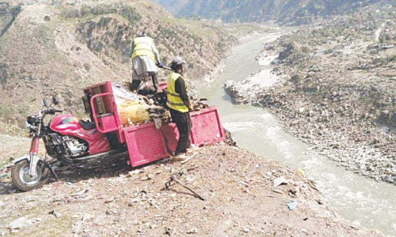 Muncipal workers throw waste into the Indus River in Shangla district. &mdash; Dawn