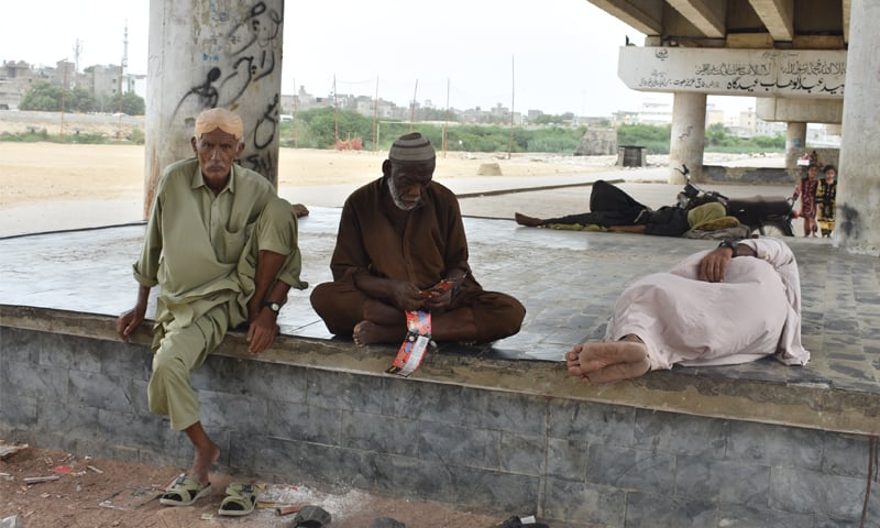 Men sit under the Lyari Expressway in Hasan Aulia Village: unlike many informal clusters, Hasan Aulia Village sits on leased land