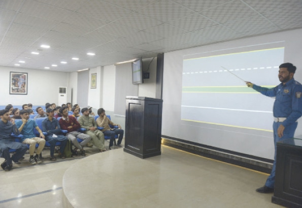 A traffic police official gives a lecture to students about safe driving.