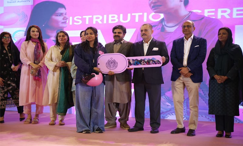 A woman receives the novelty key for an electric bike from Senior Transport Minister Sharjeel Memon during the event. &mdash;Dawn