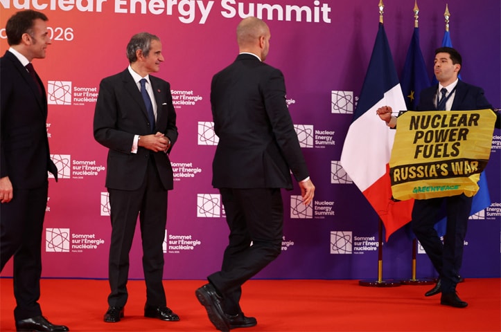 FRENCH President Emmanuel Macron and Rafael Grossi, Director General of the International Atomic Energy Agency, look on as a Greenpeace activist holds a sign in protest against the Nuclear Energy Summit.—Reuters