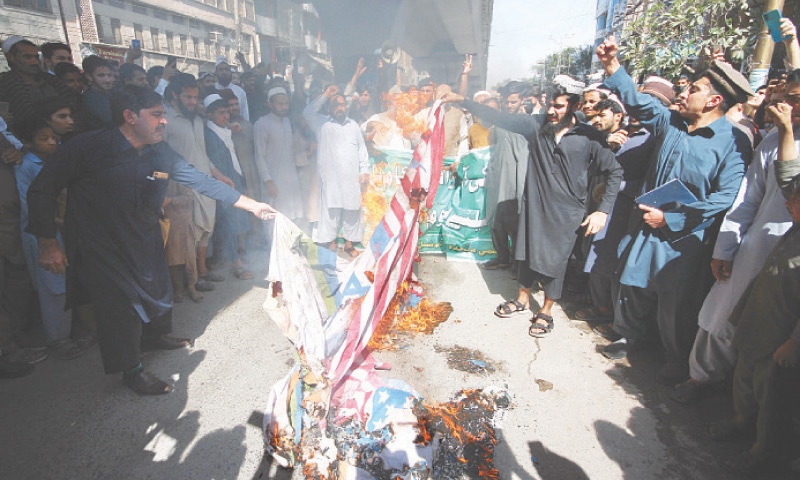 Protesters burn US and Israeli flags during a rally in Peshawar on Friday. &mdash; White Star