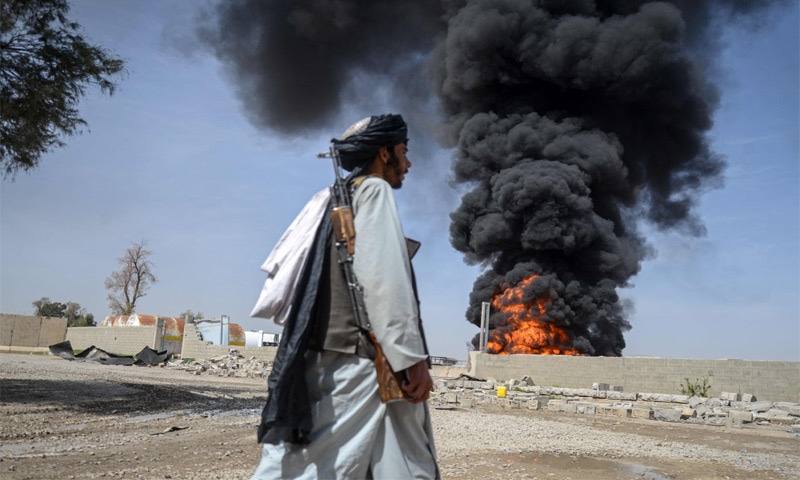 DAMAN: An Afghan Taliban fighter looks on as flames and smoke rise from an oil depot near Kandahar airport, which was targeted in overnight Pakistani air strikes against terrorist targets.—AFP DAMAN: An Afghan Taliban fighter looks on as flames and smoke rise from an oil depot near Kandahar airport, which was targeted in overnight Pakistani air strikes against terrorist targets.—AFP