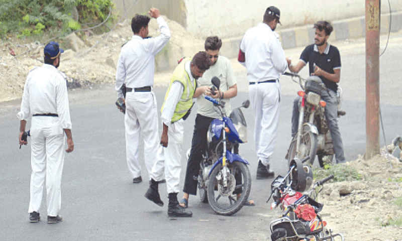 policemen stop bikers at a makeshift checkpoint near the Hasan Square flyover in Karachi .—PPI/File policemen stop bikers at a makeshift checkpoint near the Hasan Square flyover in Karachi .—PPI/File