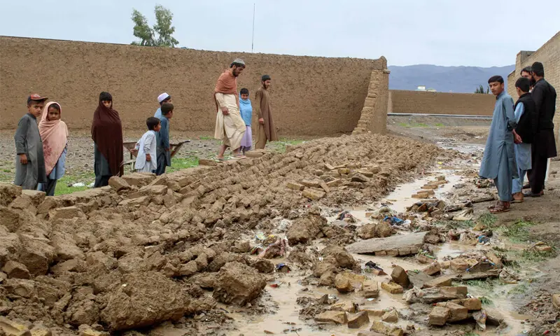 Residents gather beside the collapsed mud wall of a house during heavy rains and storm in Chaman.&mdash;AFP