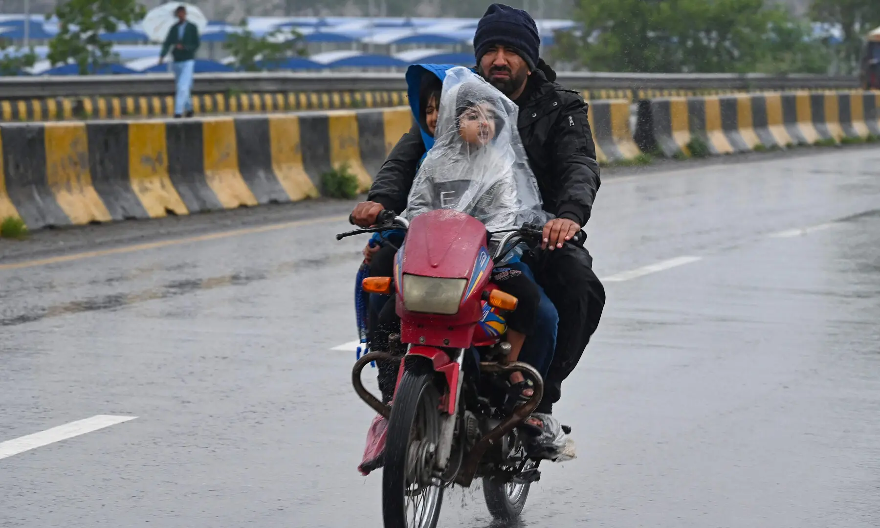 Commuters ride along a road during rainfall in Peshawar on April 3, 2026. — AFP