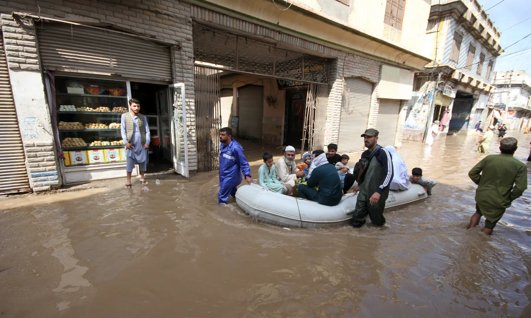 Rescuers transport people stuck in their houses due to rain water accumulated in a street at Sardar Colony to safer places in Peshawar on April 4, 2026. &mdash; Shahbaz Butt/White Star