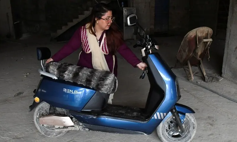 Sumaiya Rehman, 35, who works at a booking office of a constructon project, starts her electric motorcycle in Hyderabad, Pakistan April 2, 2026. &mdash;Reuters