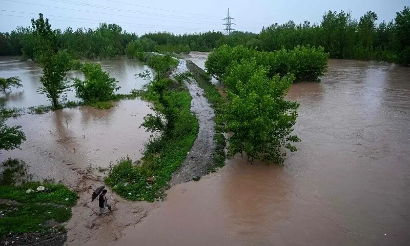 A man walks along a flooded path as torrential rains cause water channels to overflow, inundating nearby areas of Peshawar on April 7, 2026. — AFP A man walks along a flooded path as torrential rains cause water channels to overflow, inundating nearby areas of Peshawar on April 7, 2026. — AFP