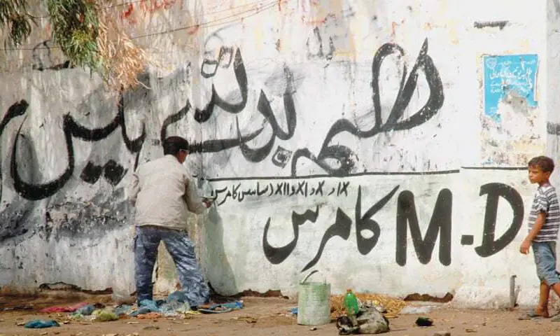 A man paints an ad on a city wall.—White Star / file A man paints an ad on a city wall.—White Star / file