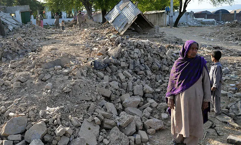 This photo shows Pakistani woman Mirjan standing in the rubble of destroyed her house at a slum area of Islamabad. &mdash; Photo by AFP