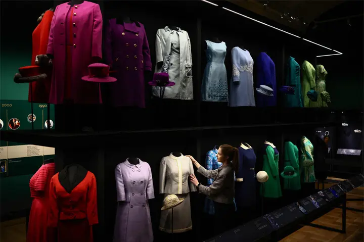 A staffer of the Royal Collection Trust poses next to a 1960 suit during a media preview of the exhibition, Queen Elizabeth II: Her Life in Style, at Buckingham Palace.&mdash;AFP