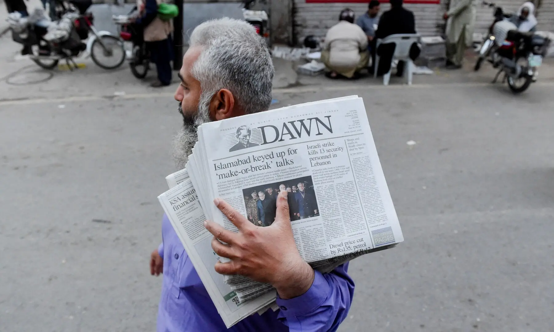A man carrying a bundle of newspapers with a headline that reads, &ldquo;Islamabad keyed up for &lsquo;make-or-break&rsquo; talks&rdquo;, walks along a street, as delegations from the United States and Iran are expected to hold high-stakes talks in Lahore, Pakistan, April 11, 2026. &mdash;AFP