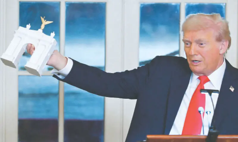 A FILE picture shows President Donald Trump holding up a model for the proposed “Independence Arch”.—AFP A FILE picture shows President Donald Trump holding up a model for the proposed “Independence Arch”.—AFP