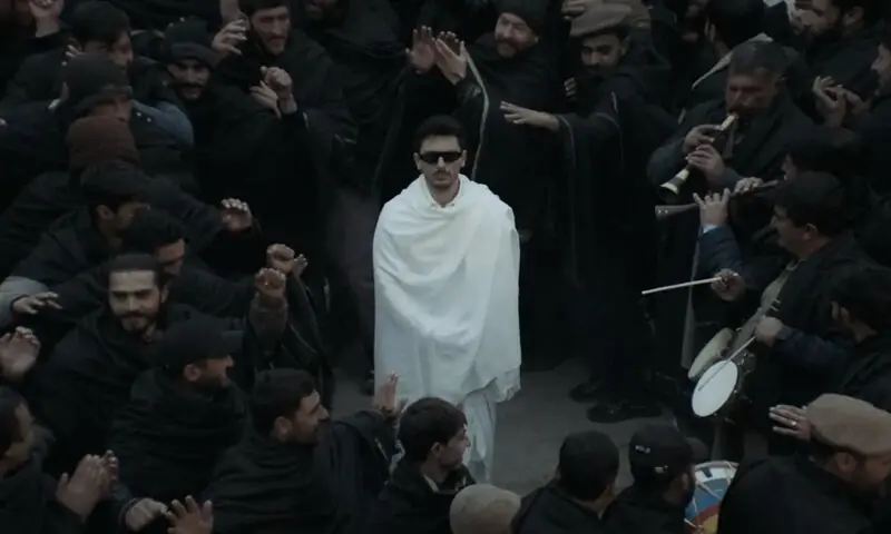 Visually striking, dressed in white and subtly adorned, Hasan Raheem stands apart from the largely black-clad crowd, embodying both observer and participant