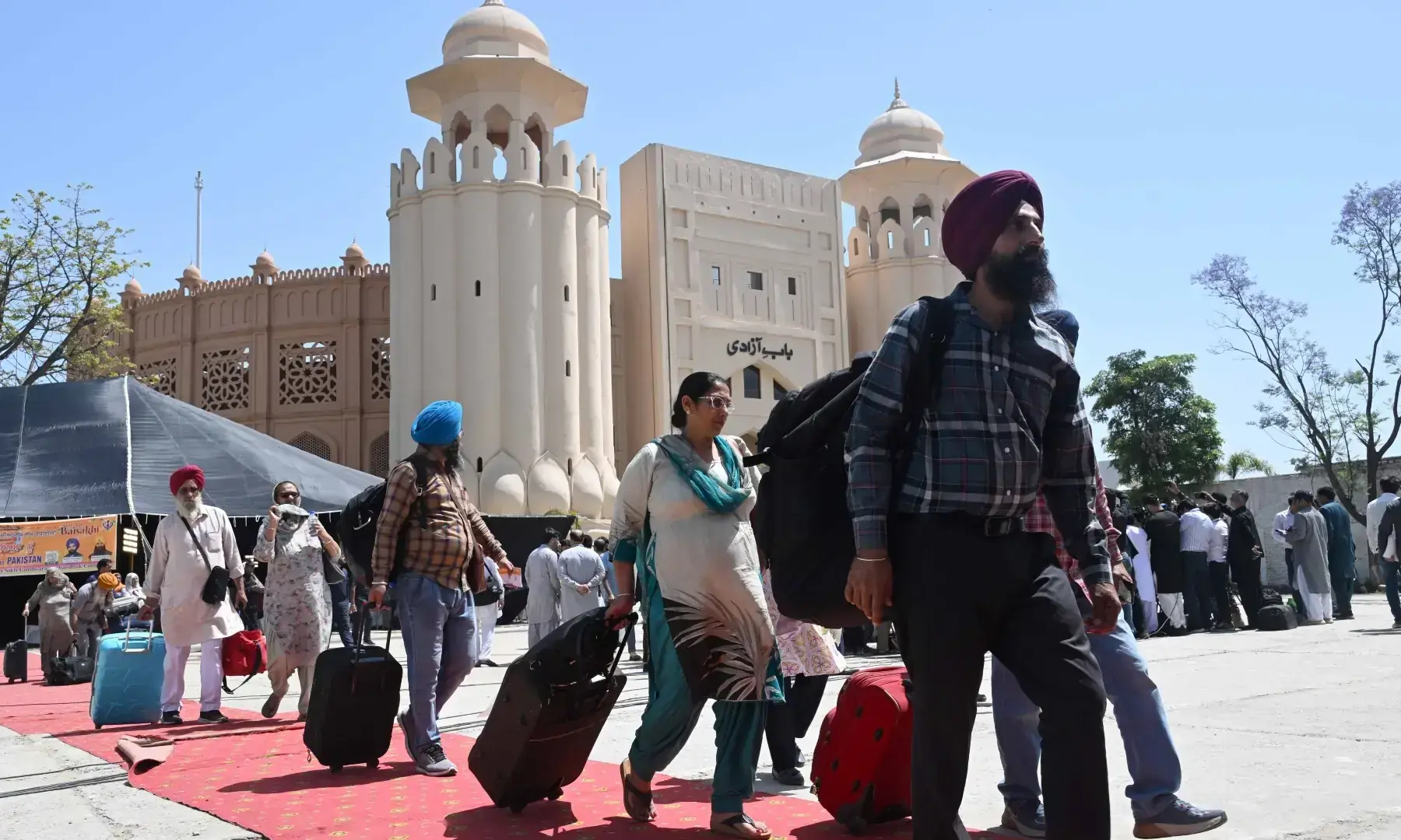 Sikh pilgrims walk with their luggage as they arrive in Pakistan from India via Wagah border on April 10. &mdash; White Star/ Arif Ali