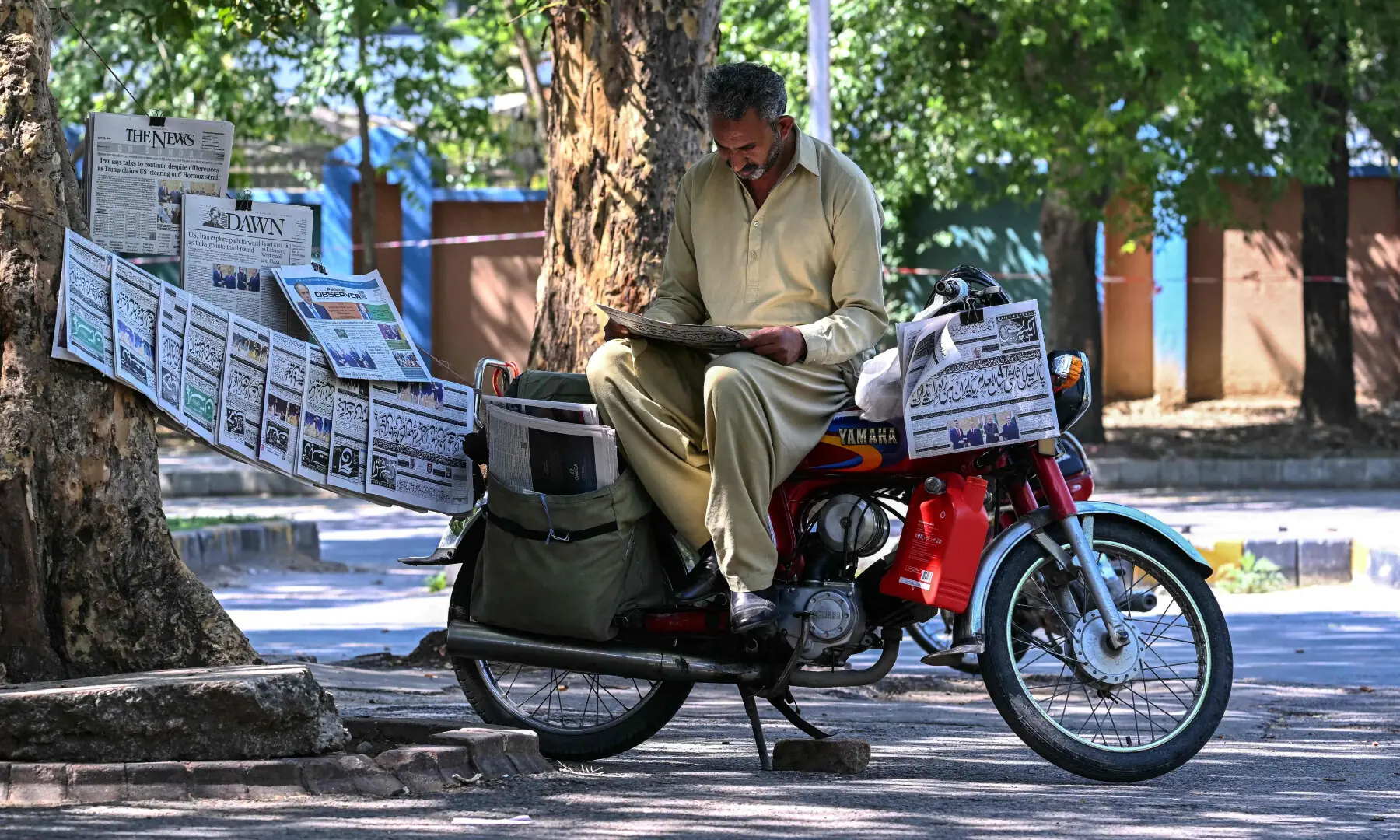 A vendor reads a newspaper displayed on a roadside after the US-Iran peace talks in Islamabad on April 12, 2026. &mdash; AFP