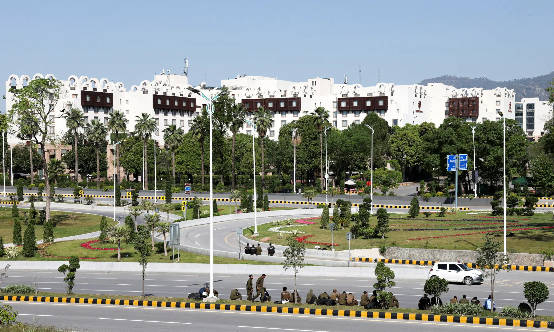 Police officers sit along a road outside the Serena Hotel, where peace talks between US and Iranian officials ended without an agreement to halt their war, in Islamabad on April 12, 2026. &mdash; Reuters