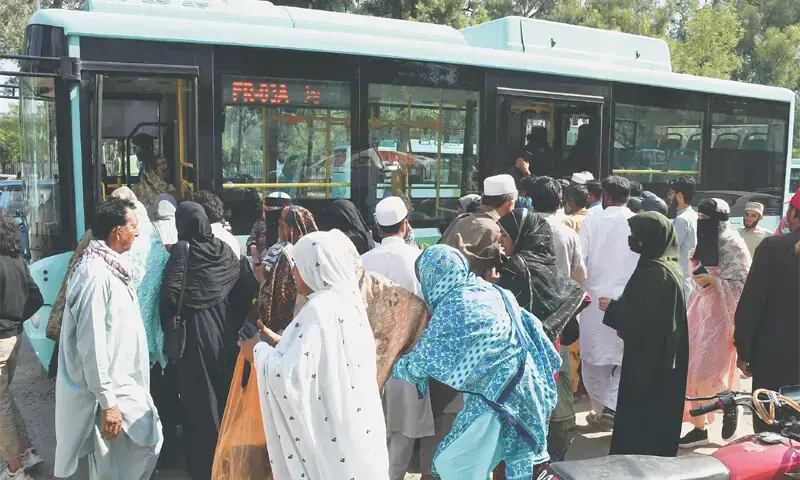 People crowd to board an electric bus at the Pims terminal in Islamabad on Monday. The federal government has announced that no fare will be charged for commuters travelling on metro, Orange, Green and Blue lines as well as e-buses for a month. &mdash; Photo by Mohammad Asim