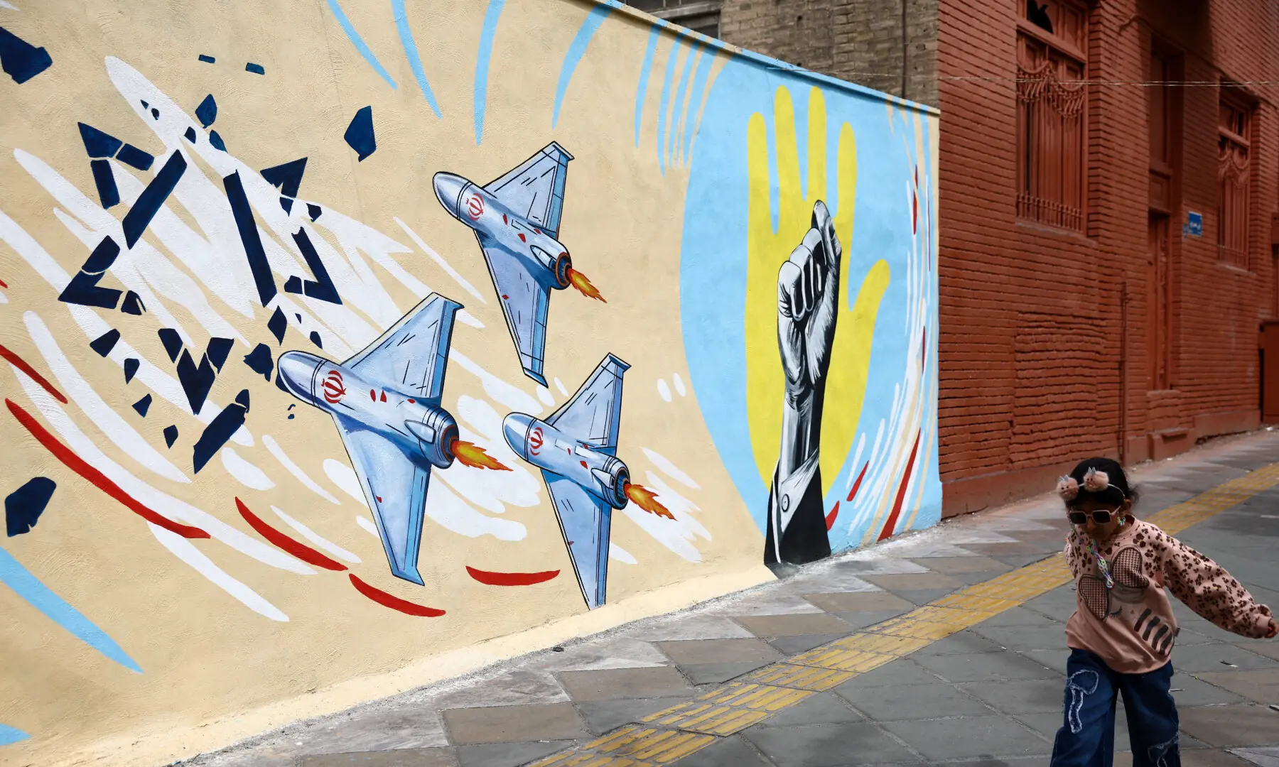A child walks next to an anti-Israeli mural on a street in Tehran, Iran, April 12, 2026. —/WANA via Reuters