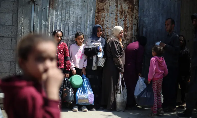 Displaced Palestinians wait to receive food from a charity kitchen at the Nuseirat refugee camp in the central Gaza Strip on April 13, 2026. &mdash; AFP