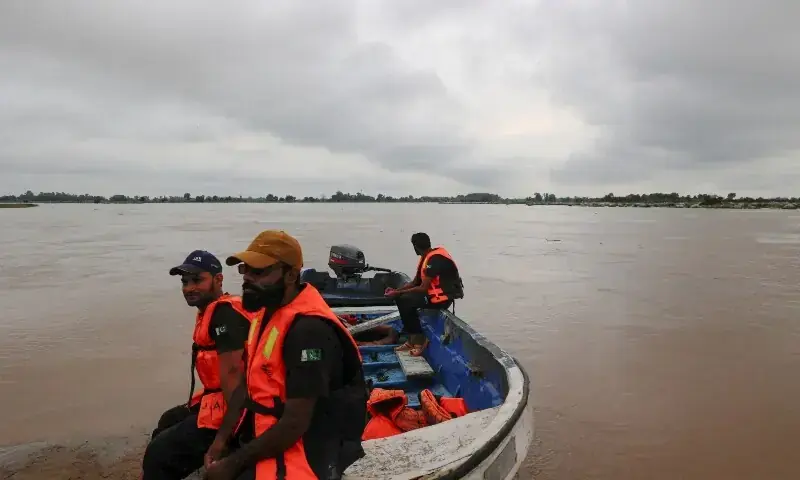 Members of the Rescue 1122 team sit on a boat with the monsoon rain clouds in the background, as they are waiting for residents to evacuate, due to the monsoon rains and rising water level of the Sutlej River, in Ghatti Kalanjar village near the Pakistan-India border in Kasur on August 24. &mdash; Reuters/File