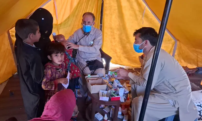 A doctor examines an Afghan woman and her children prior to their departure to Afghanistan at a free medical camp in Landi Kotal. &mdash; Dawn