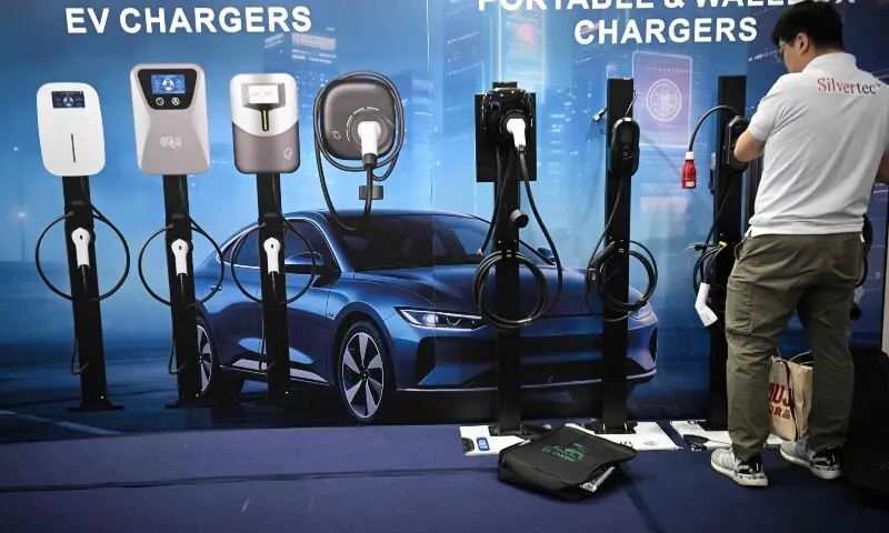 A worker arranges different types of electric car chargers made in China on display during the opening day of the International Auto Show in Manila on April 9, 2026. &mdash;AFP