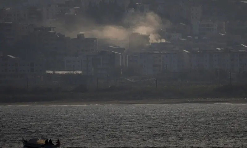 Fishermen sail their boat as smoke from an airstrike rises in Abbassiye area in Tyre, Lebanon, April 14, 2026. &mdash;AFP