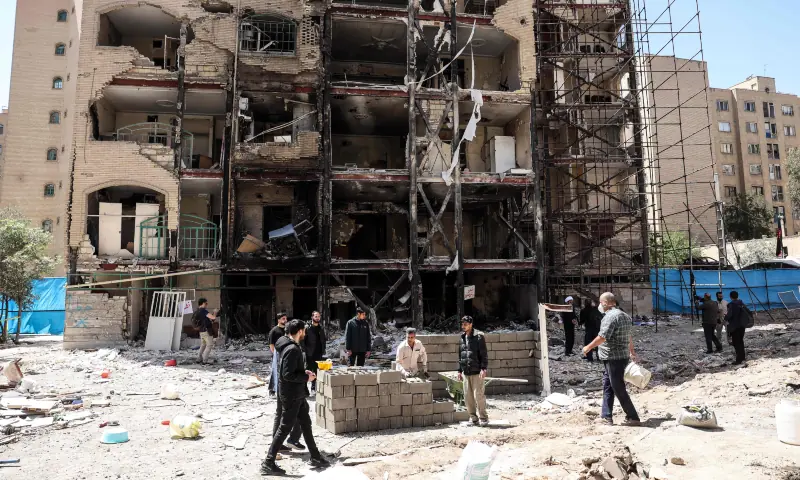 Workers and journalists stand in front of a residential building hit by US-Israel airstrikes days before a two-week ceasefire between Iran and the United States took effect, at the Shahid Broujerdi residential complex in southern Tehran on April 14, 2026. &mdash; AFP